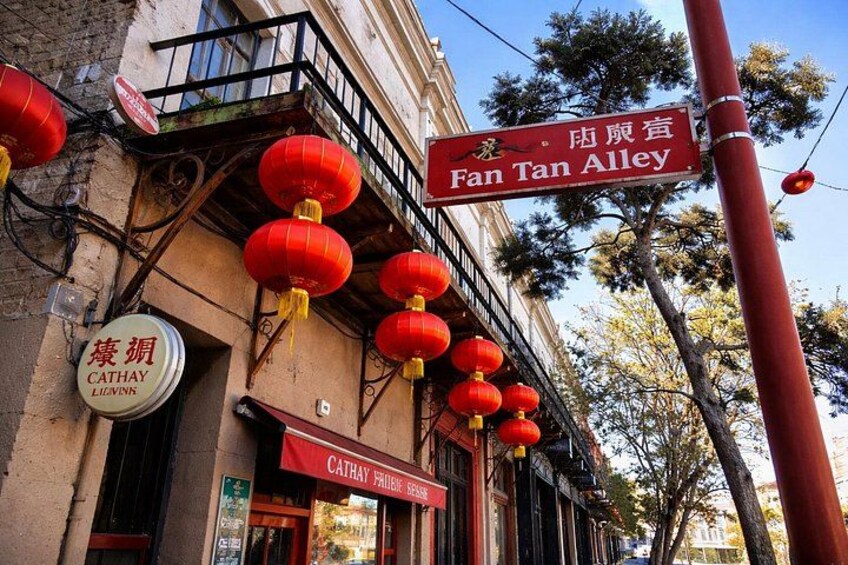 A street with red lanterns, a Cathay Liwinck sign, and a Fan Tan Alley sign. 4