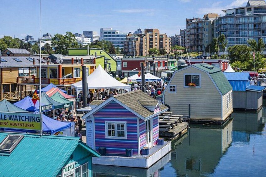 A waterfront area with colorful buildings, a dock, and a crowd of people. 2
