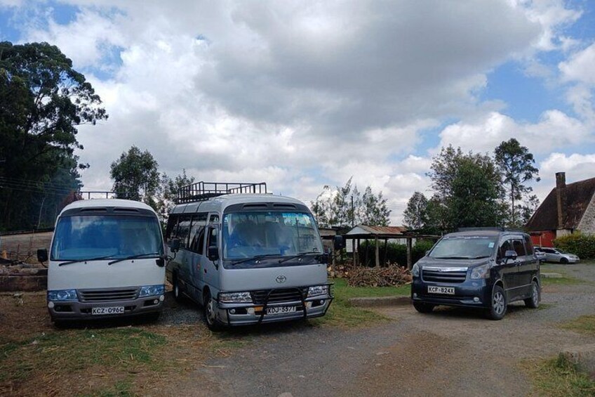 Three vehicles parked on a gravel path with a building and trees in the background. 2