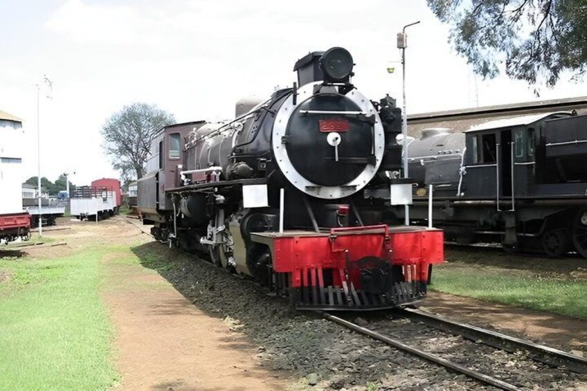 Una locomotora de vapor con una rueda delantera grande y un armazón protector rojo. 2