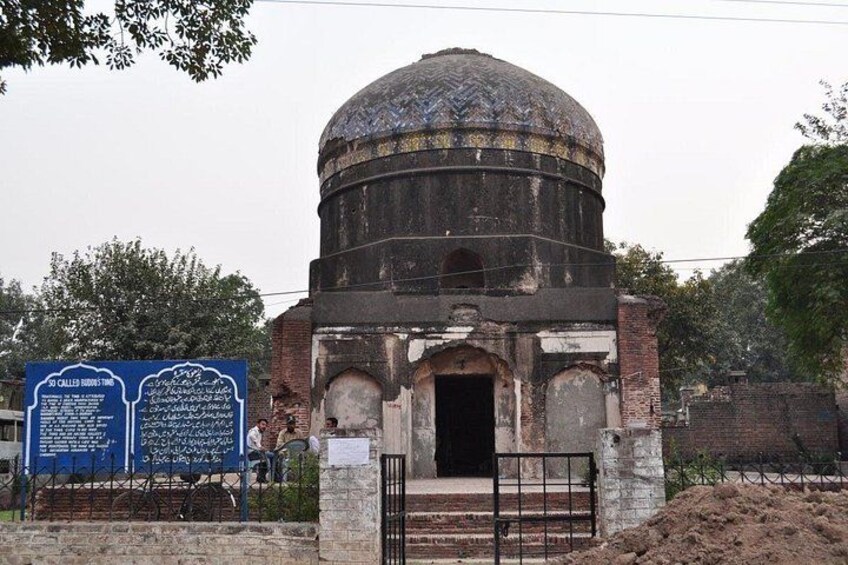 A historical building with a dome and arched entrance, surrounded by a brick wall and a metal gate. 3