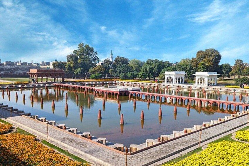 A large rectangular water body with a red bridge and white structures in a park. 4