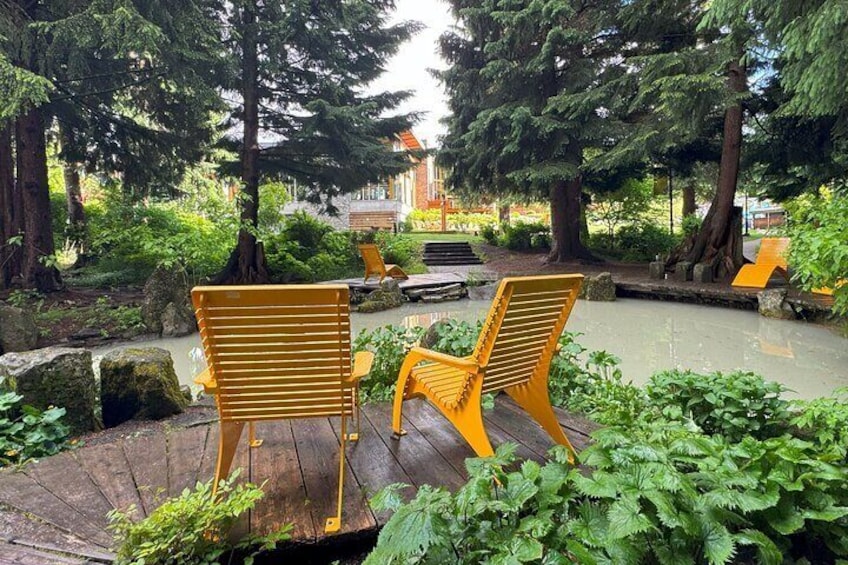 A park with yellow chairs and a pond. 5