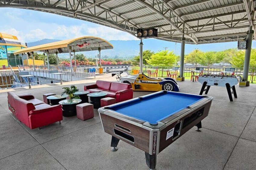 Une table de billard, des canapés rouges et une voiture jaune dans un espace extérieur. 4