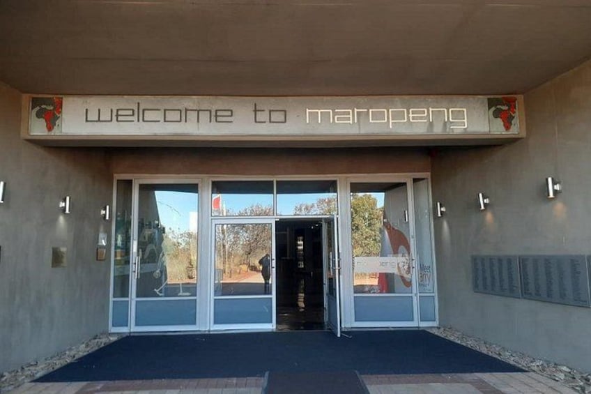 En byggnadsingång med en skylt som lyder: ”Välkommen till Maropeng”. 1