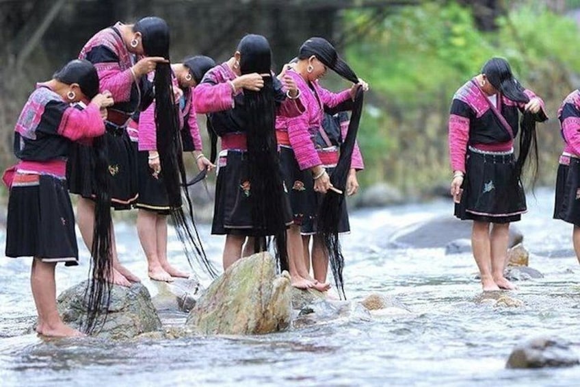 A group of people in traditional attire standing in a river. 2
