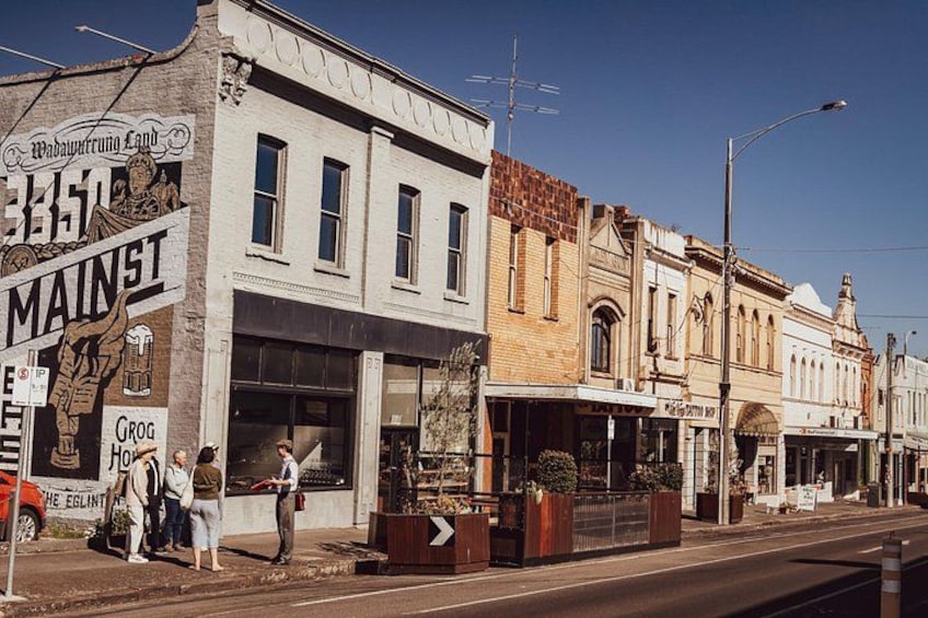 A street with buildings, a sign reading 'MAINST,' and a person standing by the sidewalk. 2