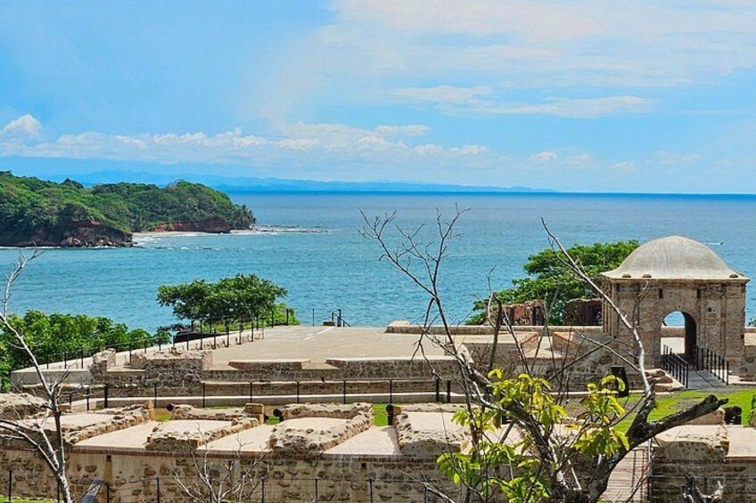 A coastal fortification with a dome structure, a clear sky, and a view of the sea. 5