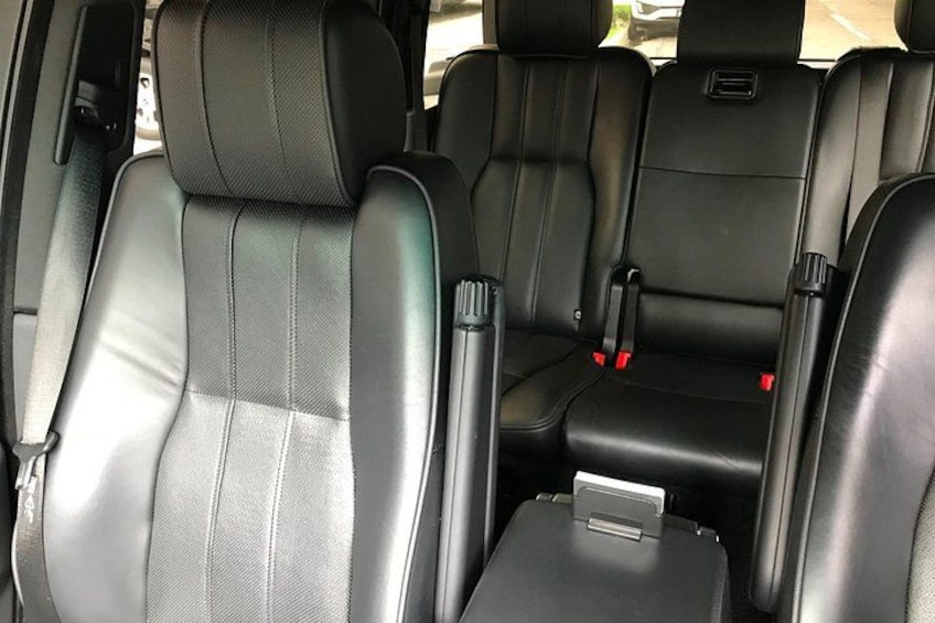 A car interior with black leather seats, seat belts, and a center console. 2