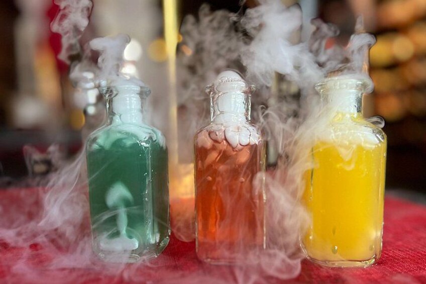 Tres botellas de vidrio con líquidos de colores y tapas blancas, emitiendo humo. 1