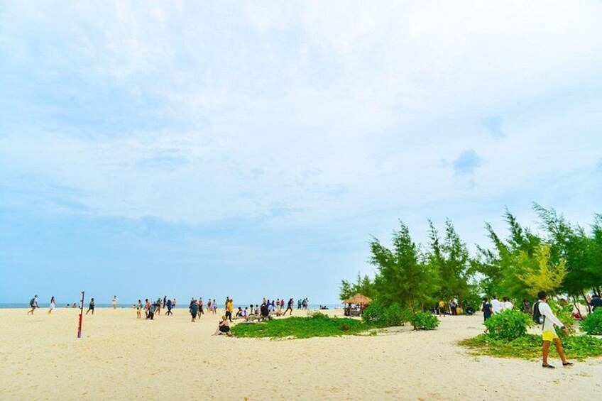 Une plage où l’on voit des gens se promener, des arbres et un ciel dégagé. 3