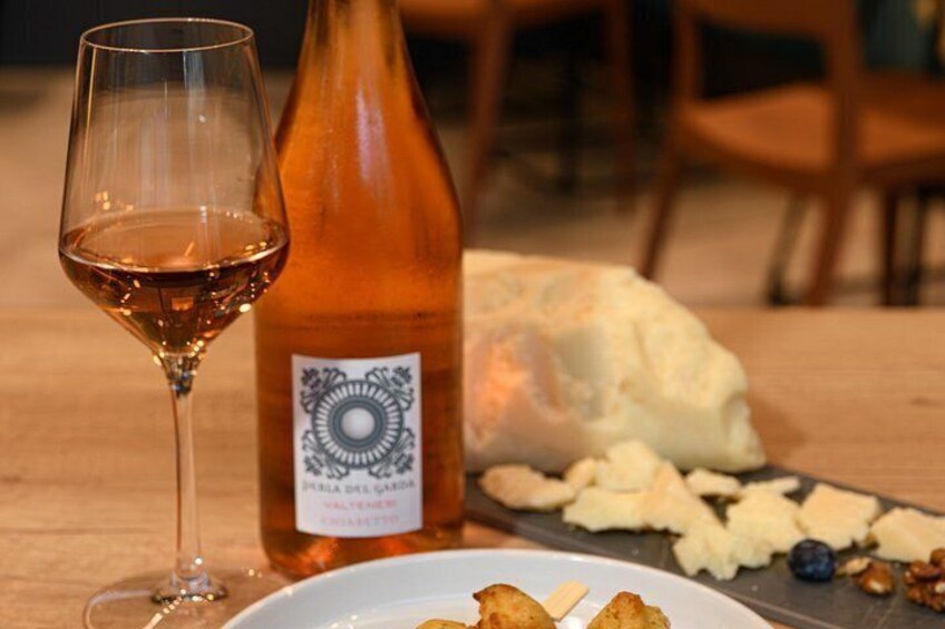 A wine glass, a bottle of wine, a plate with cheese and crackers, and a wooden table. 3