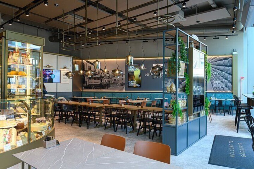 A modern cafe interior with tables, chairs, a counter, and a glass display case. 4