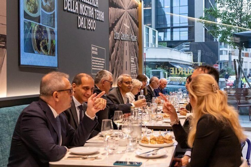 A group of people dining at a restaurant with a large menu board and a cityscape in the background. 5
