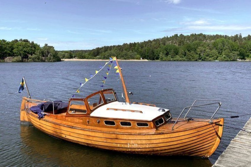 A wooden boat docked at a pier with a forested shoreline in the background. 4