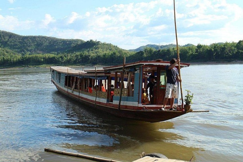 Een traditionele boot op kalm water, met een bebost landschap op de achtergrond. 5