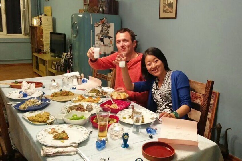 A dining table with various dishes and a person holding a drink. 1