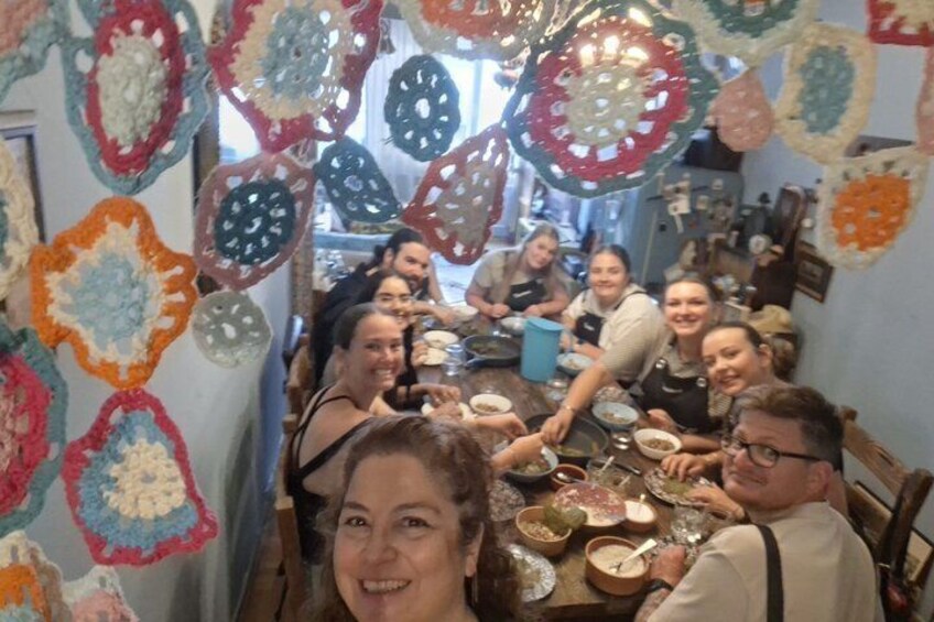 A group of people sitting around a table with crocheted decorations hanging from the ceiling. 3
