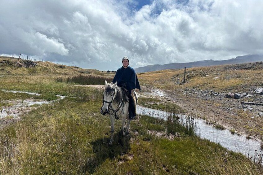 A person riding a horse on a grassy path with a cloudy sky. 4