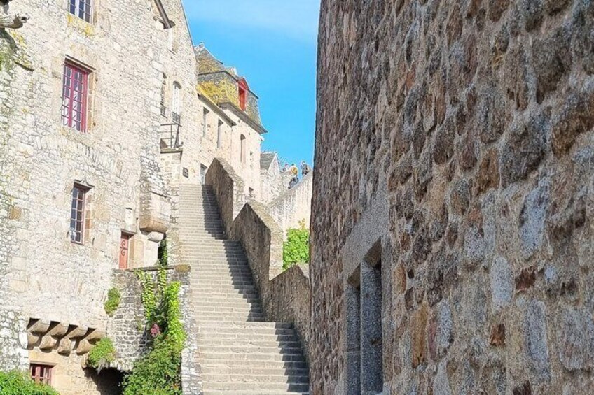 A stone staircase leading up to a building with arched doorways and a clear blue sky. 5