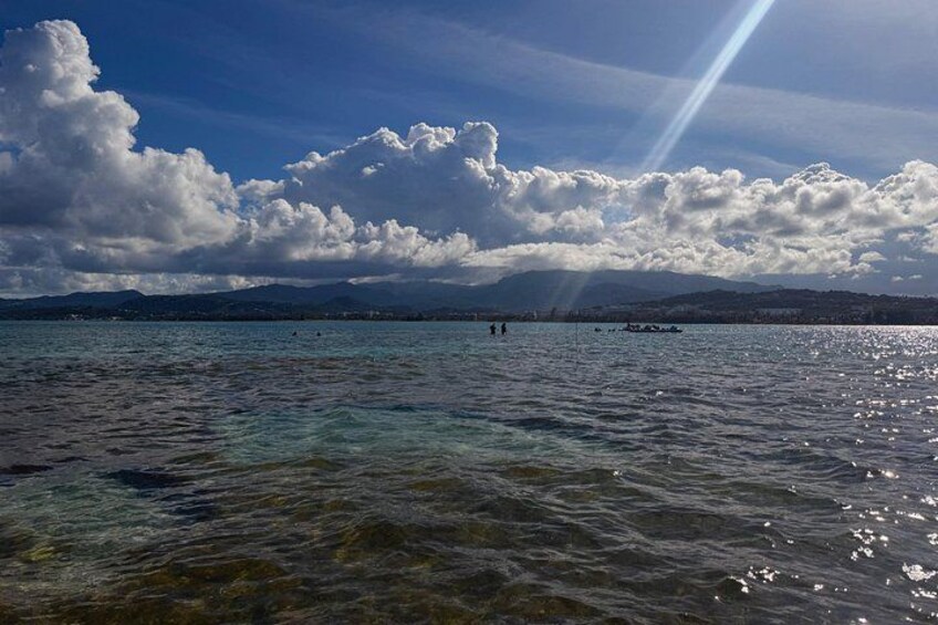 A body of water with clear visibility, a distant shoreline, and a partly cloudy sky. 5