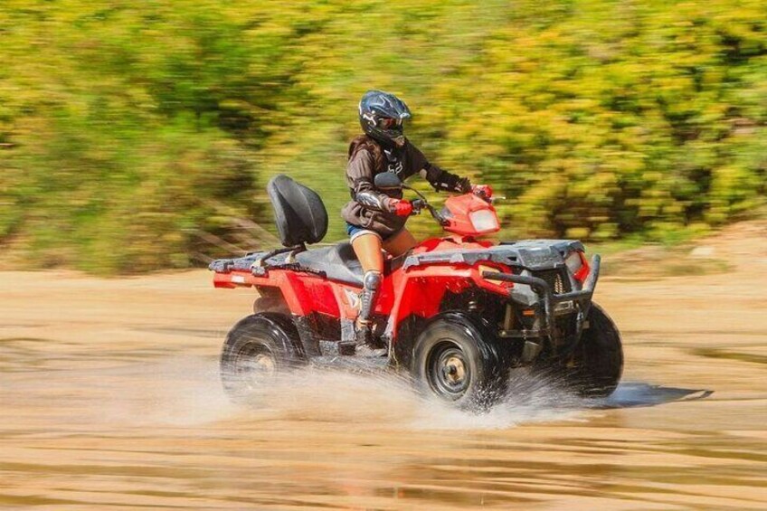 Una persona guida un quad rosso su un sentiero fangoso. 2