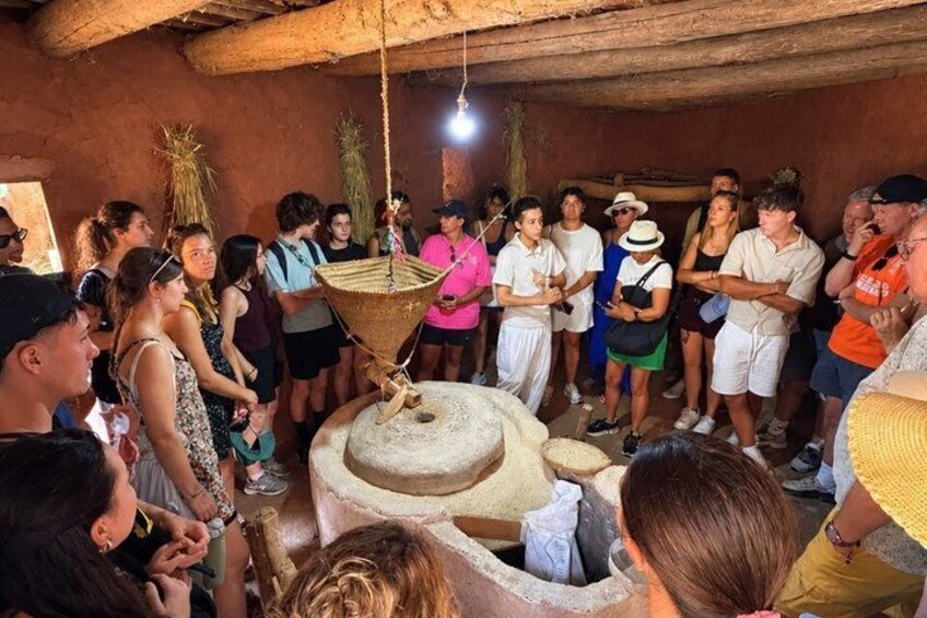 A group of people gathered around a traditional water pump in a rustic setting. 3