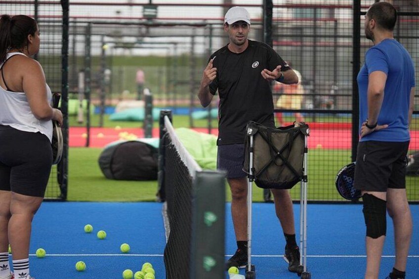 A tennis court with players and a coach. 2