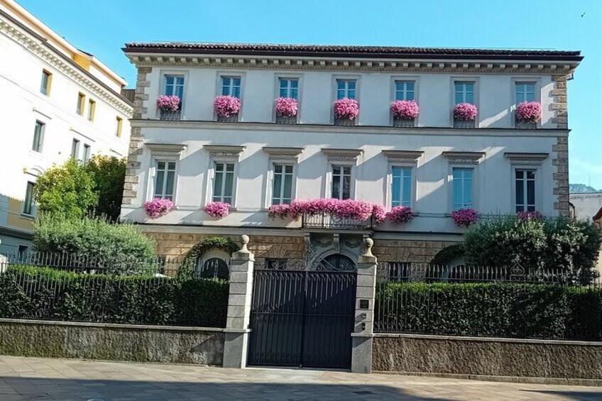 A classical building with a symmetrical facade, arched windows, and a gated entrance. 4