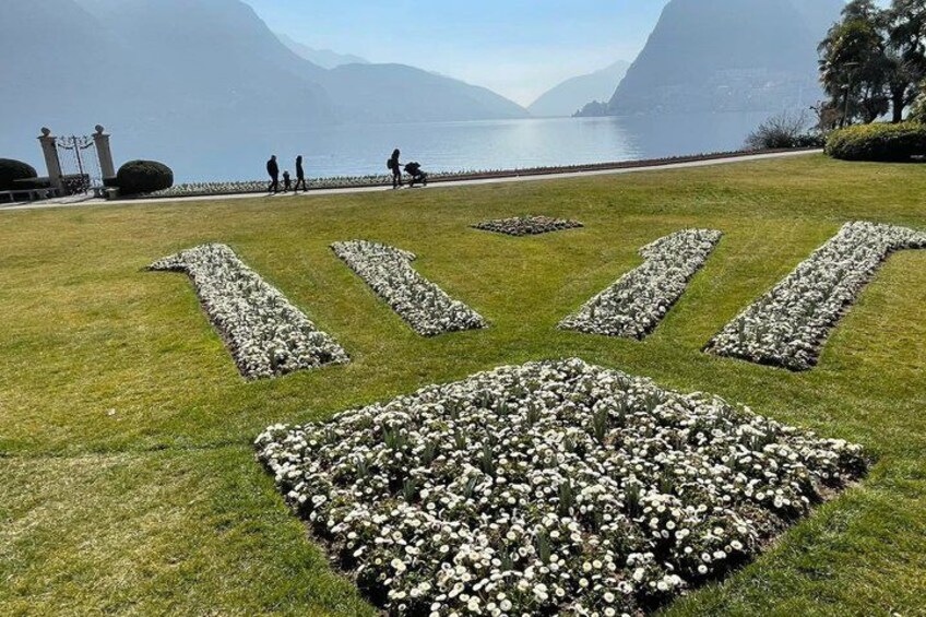 Un espacio cubierto de césped con senderos de piedra y parterres de flores. 4