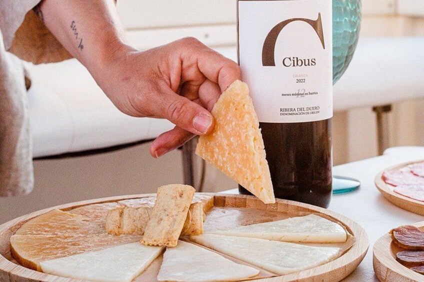 A person holding a cheese slice near a bottle of wine. 3
