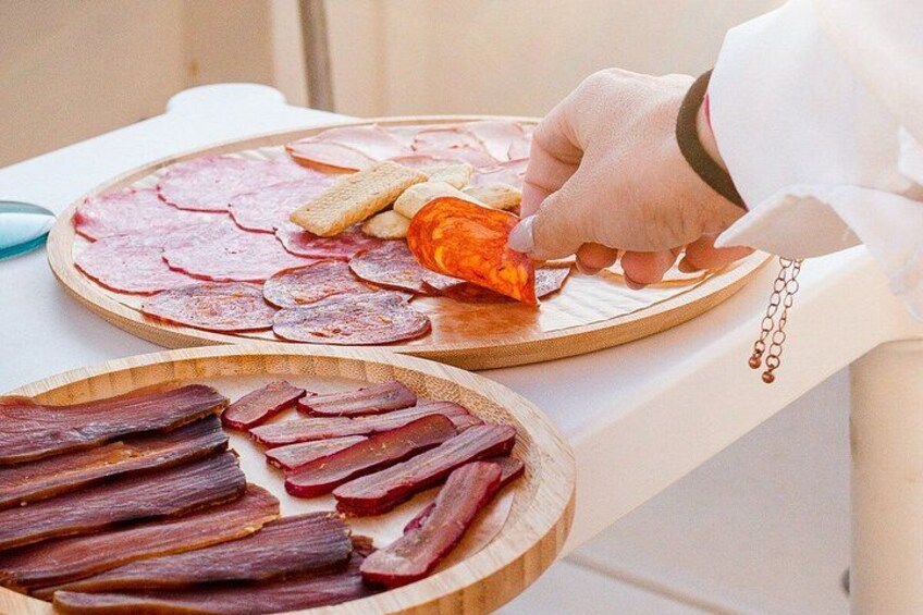 A person serving sliced meats on a wooden board. 2