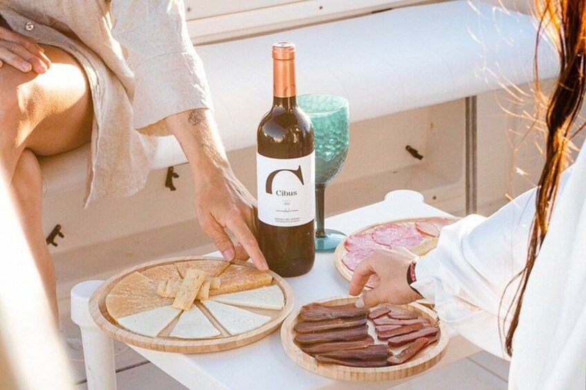 A person serving food on a wooden board, a bottle of wine, and a glass on a table. 4