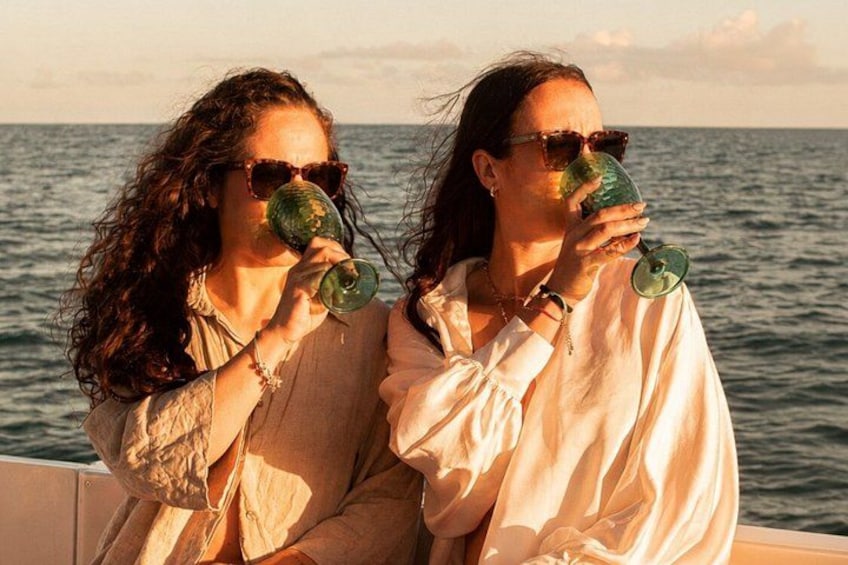 Two people sitting by the sea, holding green glasses. 5