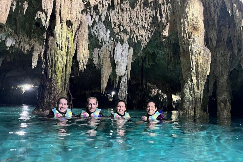 Vier Personen in einem Schwimmbecken, im Hintergrund Felsformationen. 1
