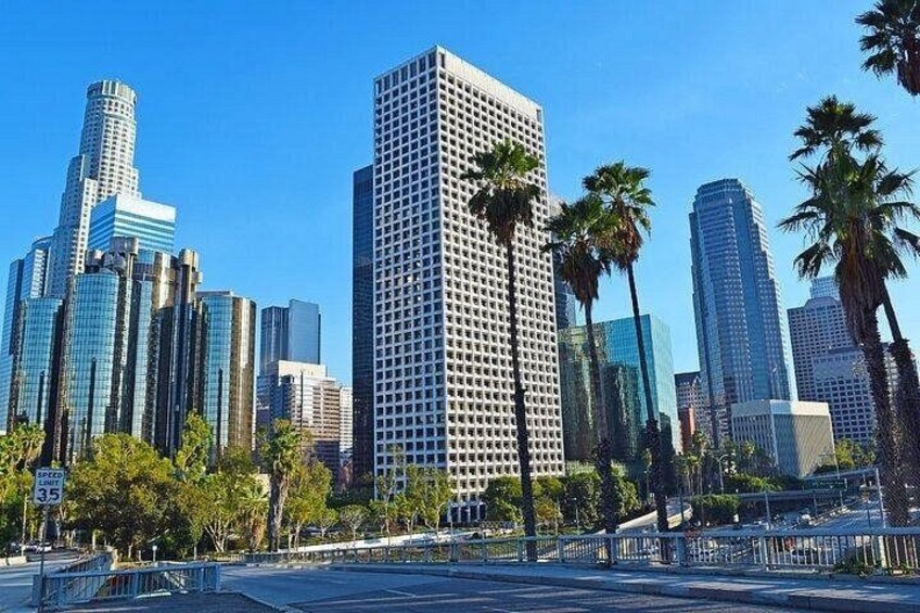 Un paysage urbain avec des gratte-ciel modernes, des palmiers et un ciel bleu dégagé. 1