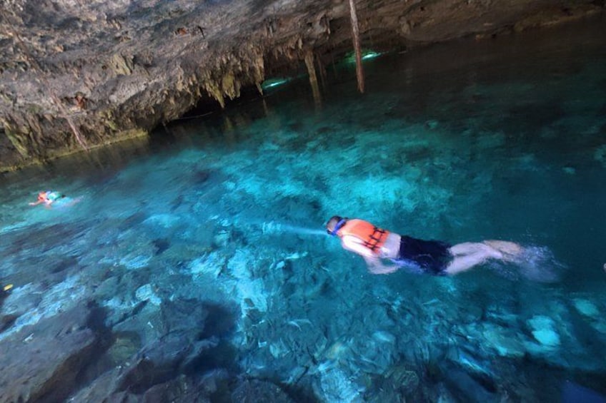 A person swimming in a clear blue pool with rocky walls. 2