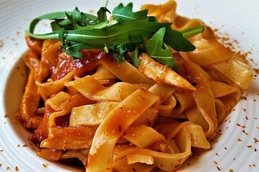 Un plato de pasta con salsa de tomate y adornado con hierbas verdes. 3