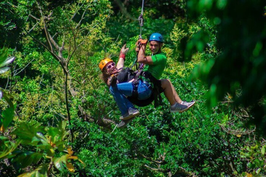 Two people zip-lining through a forest. 3