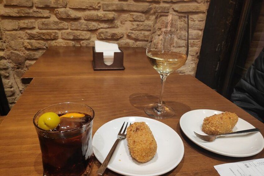 Ein Holztisch mit zwei Tellern paniertem Essen, einem Glas Eistee und einem Glas Weißwein. 2