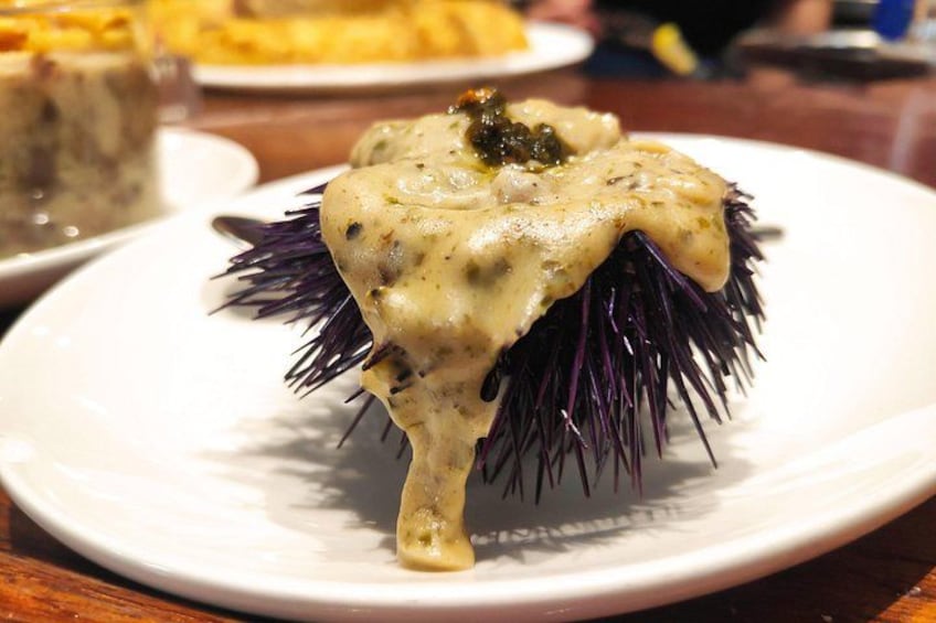 A plate with a food item covered in a creamy sauce, possibly a seafood dish, on a white plate. 4