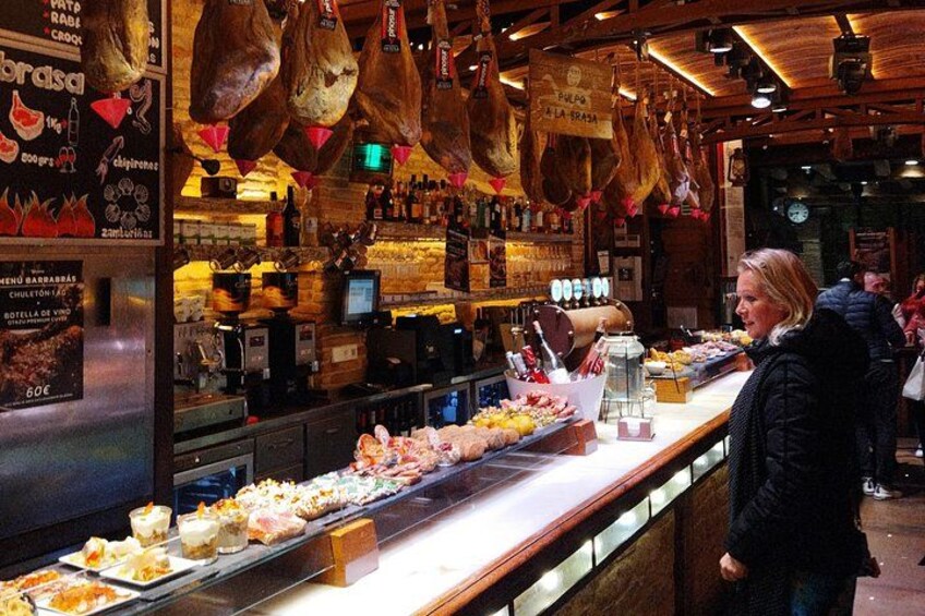 A food display with various dishes and hanging chickens. 1