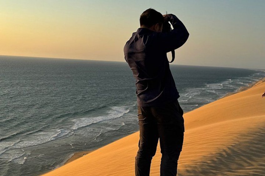Eine Person fotografiert das Meer und die Dünen. 3