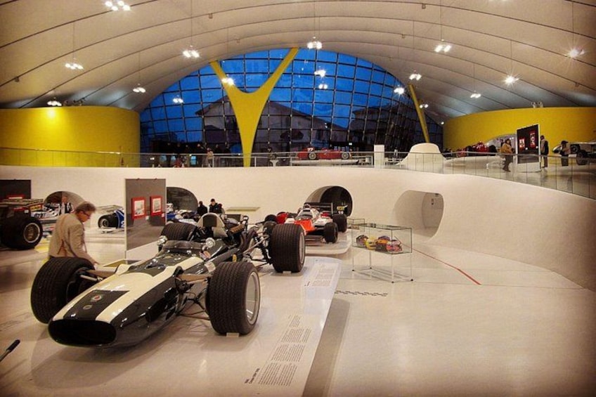 En museiinteriör med klassiska racerbilar utställda. 5