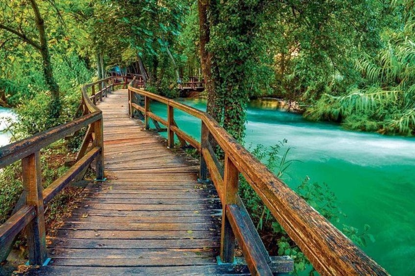 Een houten brug over een rivier, omgeven door weelderige begroeiing. 2