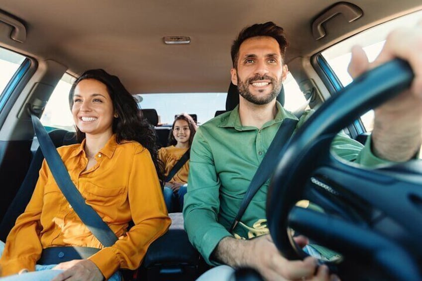 A car interior with two people driving and one person in the back seat. 1
