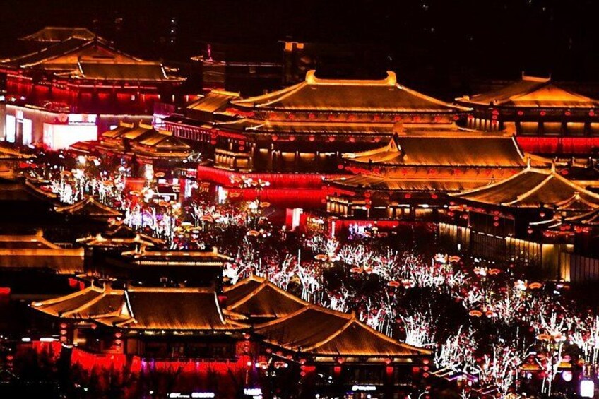 A traditional Chinese architectural complex at night with illuminated structures and a crowd of people. 4