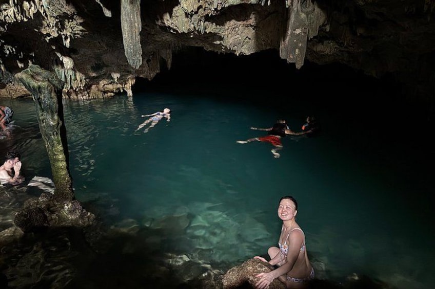 Une grotte avec de l’eau claire, des gens qui se baignent et un arbre au premier plan. 3
