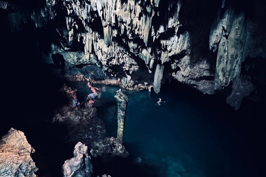 Une grotte avec des stalactites, une étendue d’eau et une personne qui nage. 5
