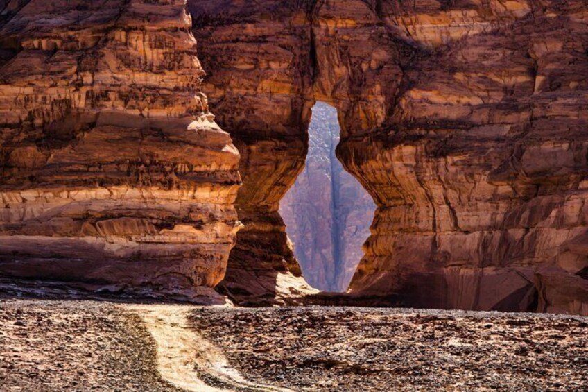 Una formazione rocciosa con un arco naturale e un sentiero sterrato che lo attraversa. 1